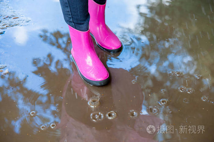 穿着橡胶靴的女人和在雨中行走的雨衣的女人