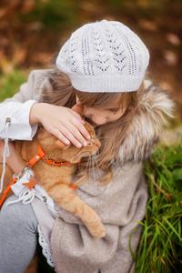 在秋天的公园里, 在秋天的公园里, 穿着复古服装的小女孩和一只红色的猫在散步