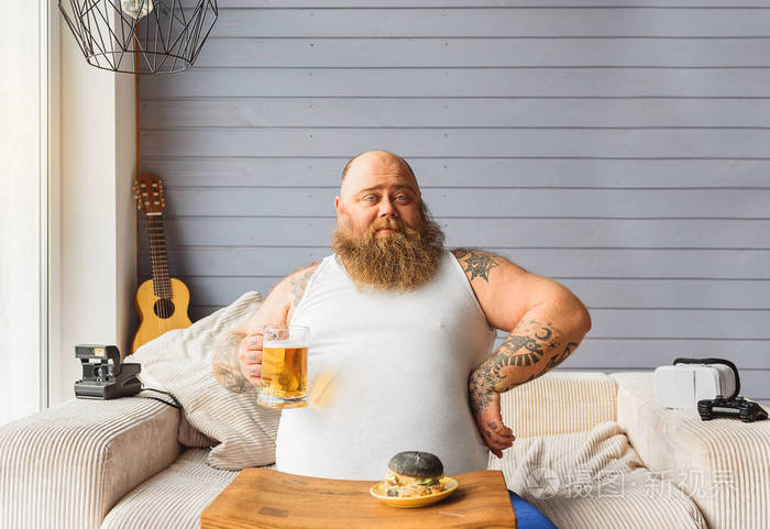 自信的胖男人休息与酒精饮料