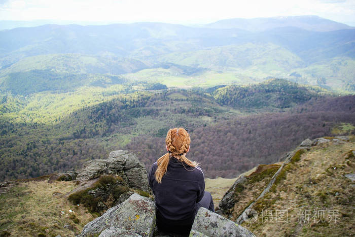这个女孩坐在悬崖边上, 看到了群山的景色.乌克兰喀尔巴阡山脉山脉.