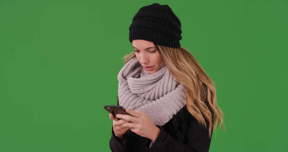 千禧一代的女人在智能手机上发短信的绿色屏幕上
