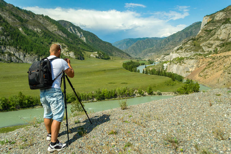 在三脚架上的照片相机年轻男子摄影师通过阿尔泰与相机在三脚架上拍摄