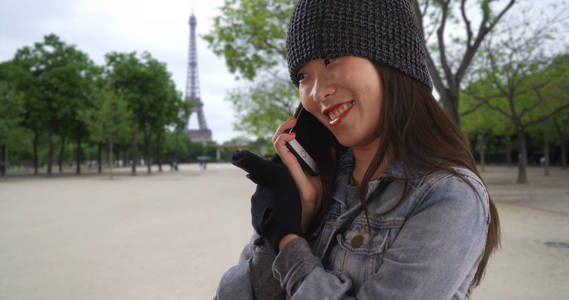 可爱的年轻女子在巴黎法国寒冷的智能手机上交谈