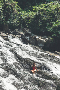 巴厘岛瀑布上穿着红色泳衣的年轻女子。印度尼西亚