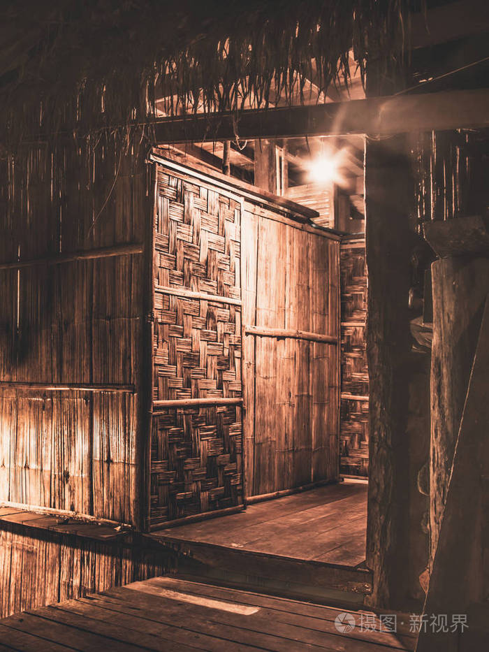 由木材和旧灯建筑墙和门纹理设计的老式老房子在夜间背景设计