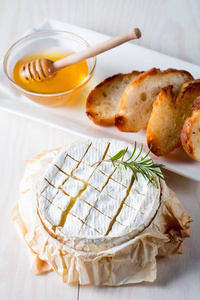 烤乳酪干酪。新鲜的芝士干酪和一块木木板上有坚果蜂蜜迷迭香法式面包烤土司和树叶。乳酪干酪。意大利, 法国干酪