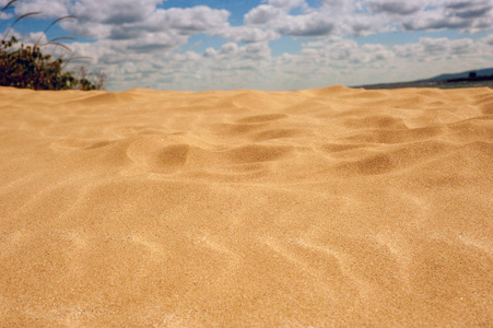 金色的沙子在炎热和阳光明媚的沙漠。黄色的沙子对蓝天与云彩