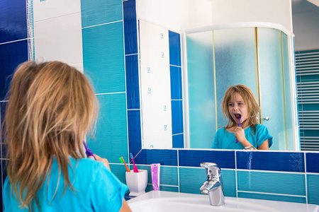 浴室里的一个小女孩一边刷牙一边看着镜子