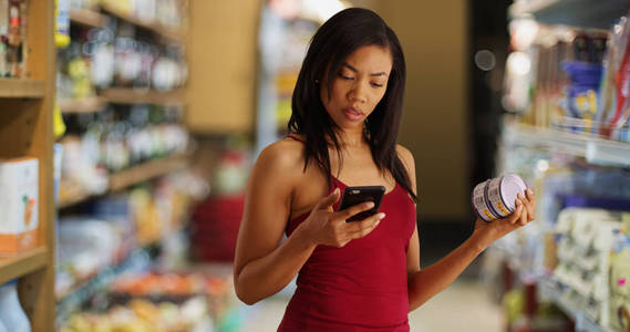 超市里的黑人妇女在用手机贴上营养事实标签