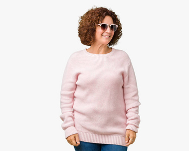 美丽的中间位高级妇女穿着粉红色的毛衣和太阳镜在孤立的背景看着一边面带微笑, 自然的表情。笑自信