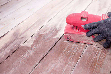 木地板抛光维修工作由磨床。男人的手戴着手套在家里修理。带木地板的磨床。复制空间。地板的修复