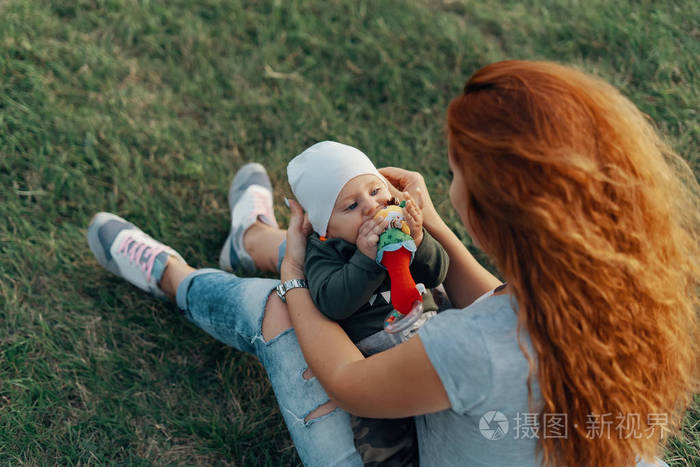 母亲把儿子抱在膝盖上.后角视图, 聚焦男婴