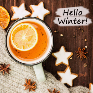 冬季主题。热茶与香料, 橘子, 八角, 饼干形状的明星, 胡椒和灰色围巾在木制背景。平的放置, 看法从上面与文本你好冬天