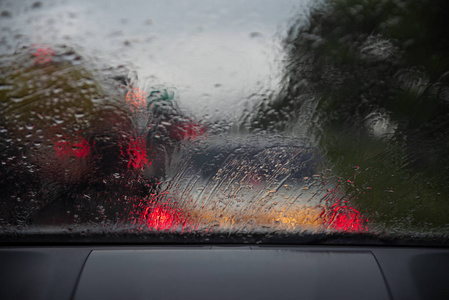 大雨。车窗上的雨滴。抽象模糊的交通和汽车灯光。大雨和背光造成的视力不佳