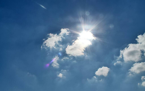 美丽的云团在蓝色和日落天空与太阳光束照片