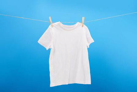 白色 t恤与衣服别针挂在晾衣绳隔离在蓝色