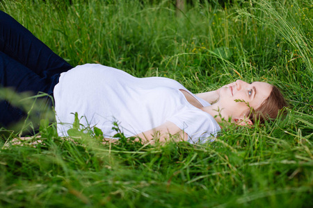 美丽的孕妇在公园的草地上放松
