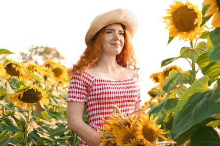 阳光明媚的日子, 美丽的红发女人在向日葵地里