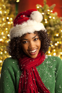 在圣诞树前戴着圣诞老人帽子的快乐年轻女子的亲密