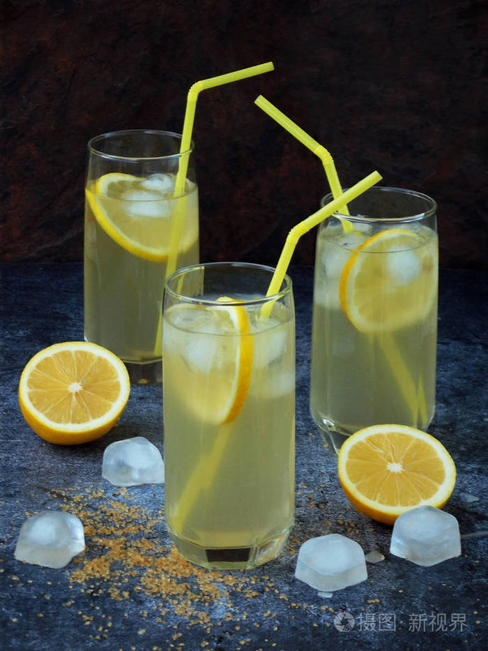 三杯冷自制柠檬水柠檬片, 冰块, 红糖和秸秆在深色背景上.复制空间