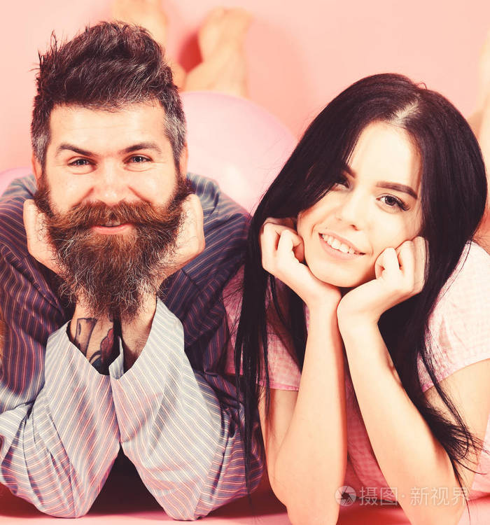 男人和女人在笑脸上躺着, 粉红色的背景.相爱的情侣在一起快乐.