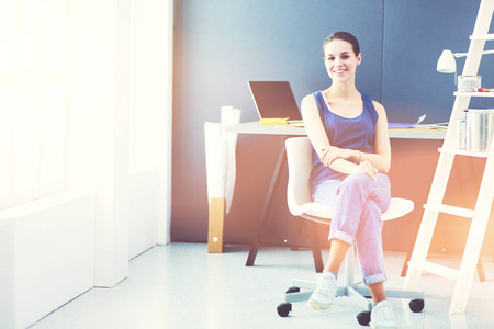 年轻的女人坐在办公桌前与文书 计划和笔记本电脑