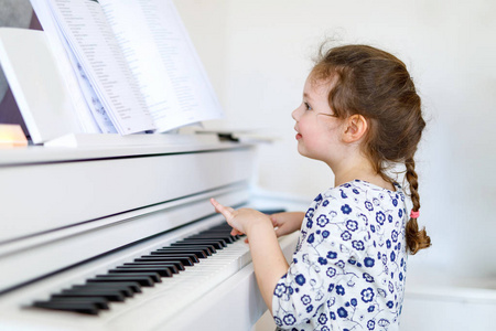 漂亮的小孩小女孩弹钢琴在或音乐学校