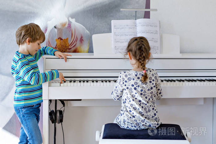 两个小孩子弹钢琴在客厅或音乐学校的男孩和女孩