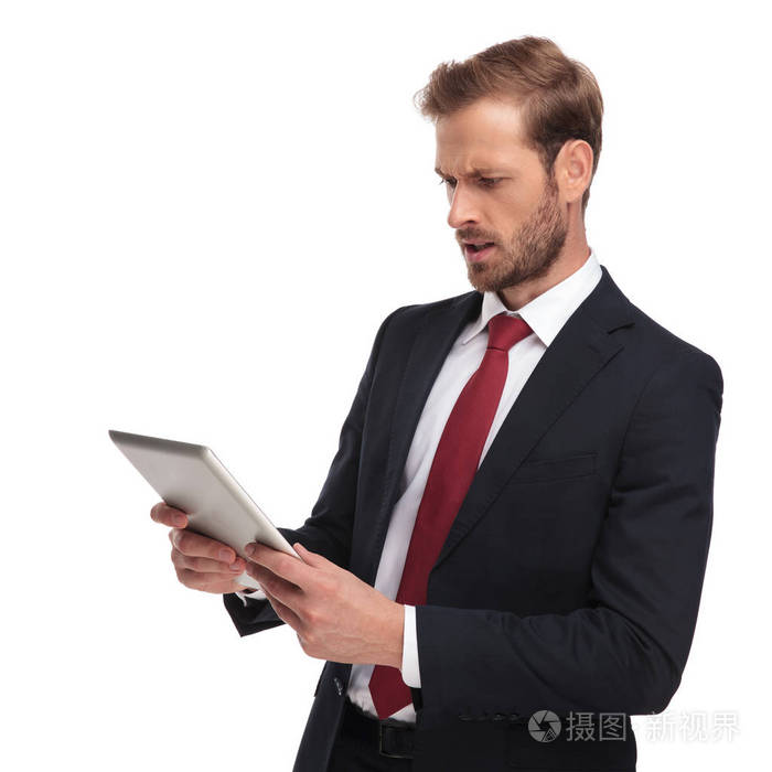 侧面看到的震惊商人身穿红领带和海军西装阅读从他的垫, 而站在白色