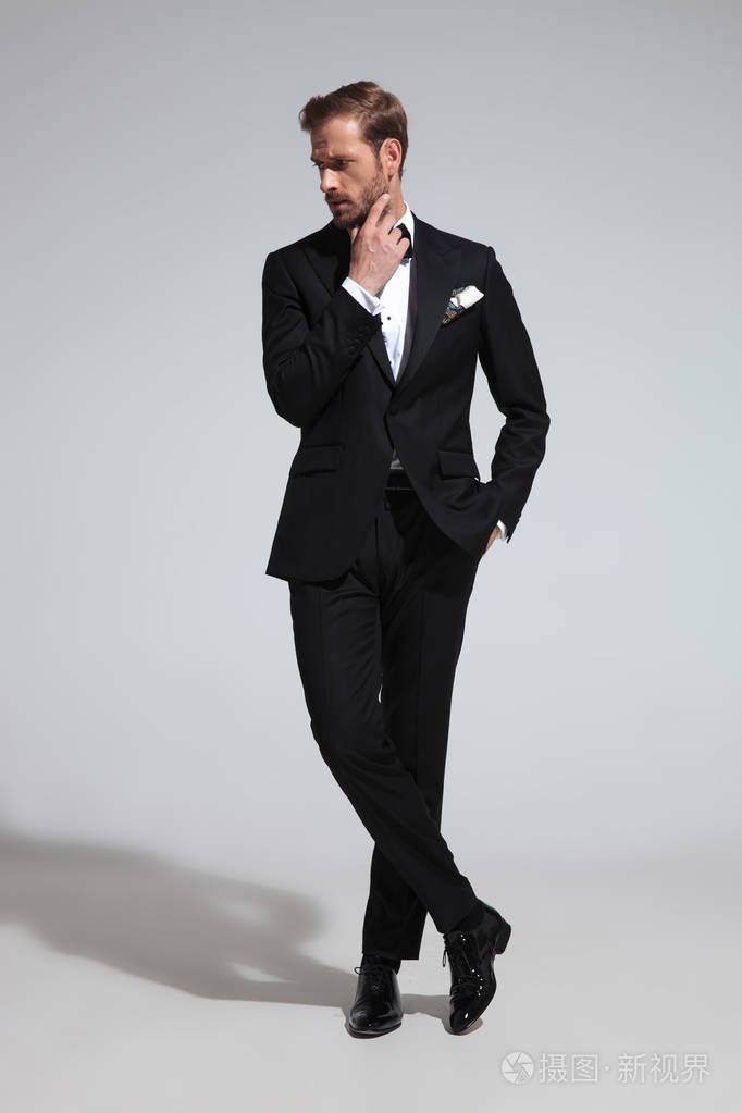 一个沉思优雅的男子在燕尾服的侧面看着灰色背景