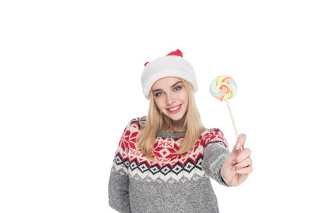 年轻女子的纵向毛衣和圣诞老人帽子与棒糖查出白色