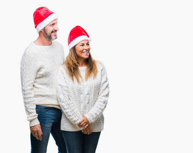 中世纪的拉美裔夫妇戴着圣诞帽子在孤立的背景下, 脸上露出笑容, 自然的表情。笑的自信