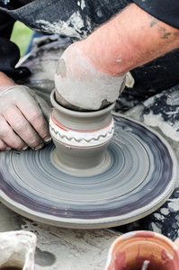 用轮子上的粘土制作陶器的手的特写镜头。
