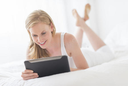 女性躺在床上使用数码平板电脑