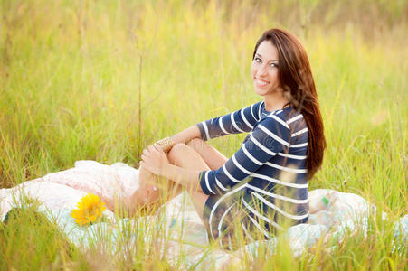 一个女孩坐在一个有向日葵的地里的被子上