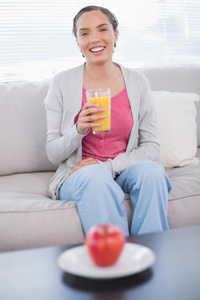 坐在沙发上拿着橙汁的快乐女人