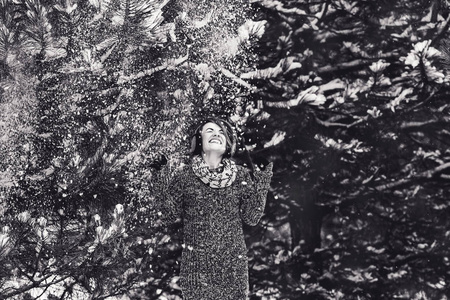 在冬季森林的毛衣时尚开朗的女孩。树上的雪落在女孩身上