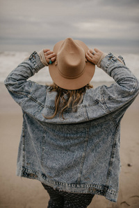一个戴着帽子欣赏海洋风景的女人的后景色