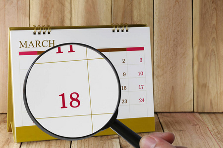 放大镜在手上日历你可以看十八天的月份, 焦点十八在 3月, 商业和会议的概念