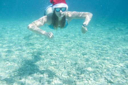 在水下游泳在大海里，圣诞假期在海上概念的圣诞老人帽子的女人