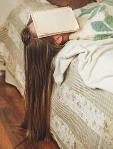 美丽的年轻女子睡在床上, 脸上覆盖着她的脸, 因为阅读书籍与准备大学考试