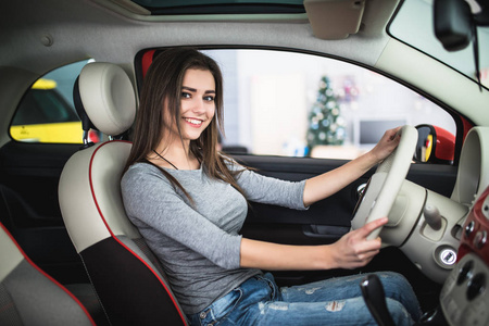 谁有开车的年轻有魅力的女人微笑,看着相机在开车时照片