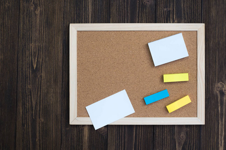 木制桌上的空软木板和记事本上的粘纸, 带有复制空间的顶部视图, 用于添加文本和邮件