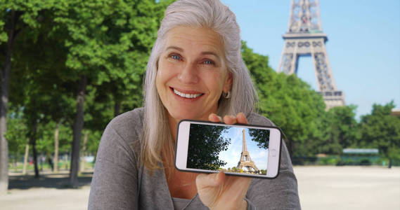 巴黎快乐的白人老女在智能手机上展示埃菲尔铁塔的照片