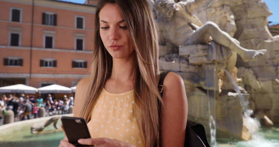 快乐的千禧女孩采取自拍与智能手机由菲米喷泉在罗马