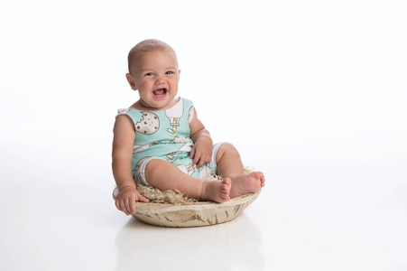 一个笑着七月大的小男孩坐在一个简陋的木碗里。拍摄在演播室在白色, 无缝的背景