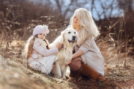 小女孩和她的母亲户外与金色猎犬