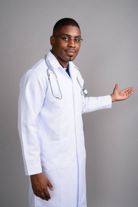 年轻英俊非洲人医生反对灰色背景