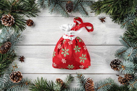 创意框架由圣诞树树枝和松果在白色木背景与圣诞包。圣诞节和新年主题。平面布局, 顶部视图