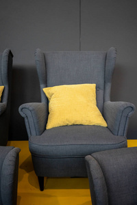 灰色织物椅子与黄色枕头对深灰色背景